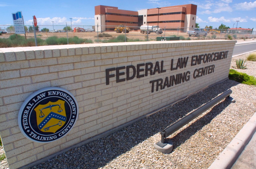 Federal Law Enforcement Training Center sign with a building under construction in the background.