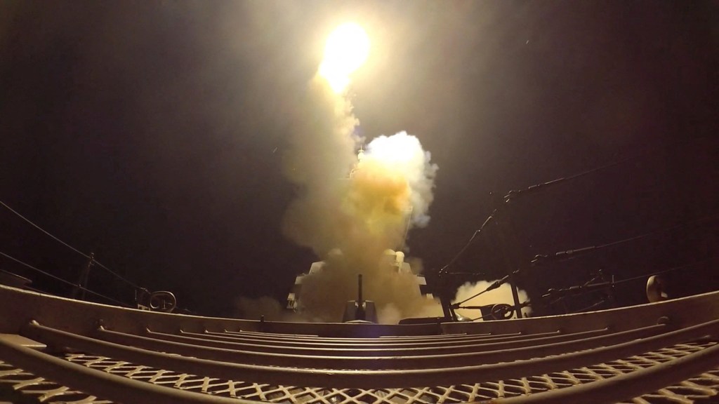 A projectile launching from a ship at night, emitting bright light and smoke.