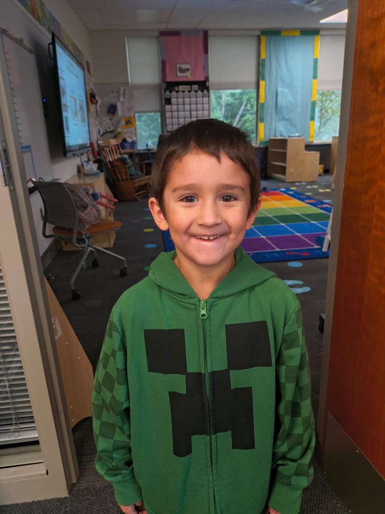 Killian Gonzales, a 6-year-old boy, smiling while wearing a green Minecraft-themed hoodie.