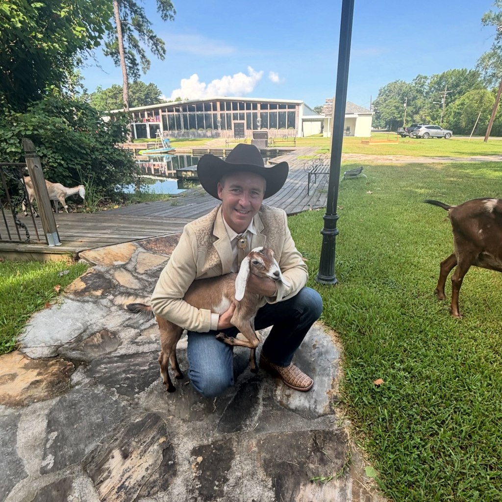 Tony Spell, a Louisiana pastor, kneeling and holding a goat.